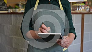 The waitress takes orders from customers in the cafe. Successful small business owner wearing a casual gray apron