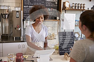 Waitress taking a customerï¿½s order at till in a coffee shop