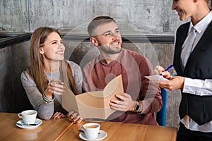 Waitress taking and order from young couple in restaurant