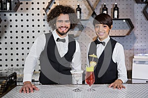 Waitress and waiter standing in bar counter with glass of cocktail