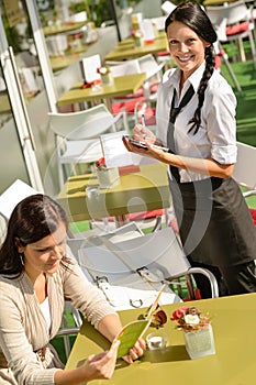 Waitress waiting for woman to order menu