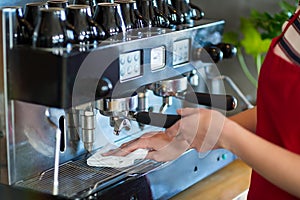 Waitress wiping espresso machine with napkin in cafÃƒÂ©