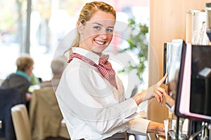 Waitress working at coffee machine in bakery or cafe