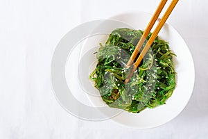 Wakame Chuka or seaweed salad with sesame seeds in bowl on white background.