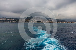 Wake in blue water leaving port of Savona, Italy