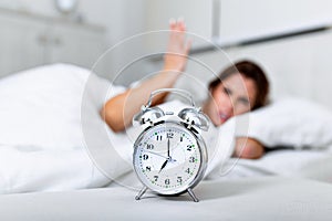 Wake up of an asleep girl stopping alarm clock on the bed in the morning. woman sleeping and wake up to turn off the alarm clock