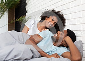 Happy young couple waking up in morning in bed