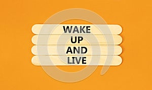 Wake up and live symbol. Concept words Wake up and live on wooden stick. Beautiful orange table orange background. Business