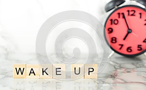 Wake up scrabble text on marble desk with alarm clock on the background