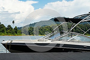 A wakeboard boat at a wooden dock in the Kenyir Lake on a sunny day