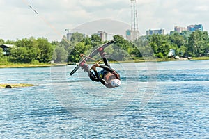 Wakeboarder jumps from a springboard behind a rope and makes a wave on the water