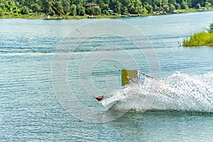 Wakeboarder jumps from a springboard behind a rope and makes a wave on the water