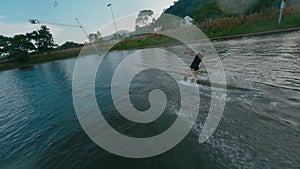 Wakeboarder man jump 360 trick ride water cable wakeboard park jibbing figure