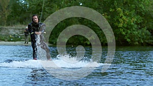 Wakeboarder riding on tranquil water. Male rider extreme life
