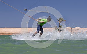 Wakeboarding sportsman jumping high in the cable park, water sports