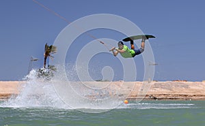 Wakeboarding sportsman jumping high in the cable park, water sports