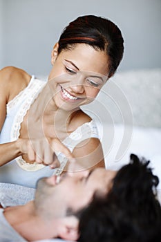 Wakey wakey. Playful woman lying alongside her boyfriend in bed.