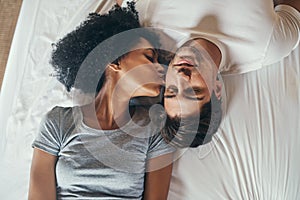 Wakey, wakey sleepy head. High angle shot of a young woman kissing her boyfriend on the cheek while lying in bed photo