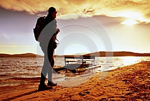 Walk along sea. Man with backpack walk on beach at rusty pedal boat. Autumn at sea.