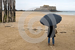 Woman with an umbrella on the Sillon beach facing the Forrt National in Saint-Malo photo