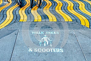 Walk Bikes and Scooters sign on ground