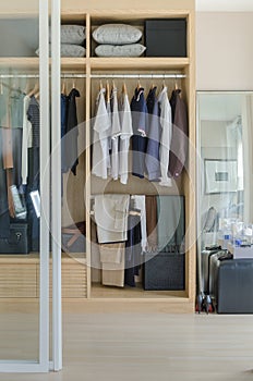 Walk in closet with clothes hanging in wooden wardrobe