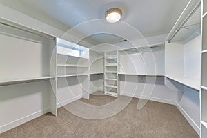 Walk in closet of house with empty built in shelves and two levels clothing rods