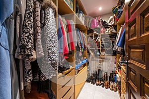 walk-in closet with wooden shelves, drawers and full of clothes on the hangers