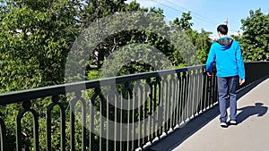 Walk men with disabilities in the city. He approaches the fence of the bridge and admires the view. Lameness, cerebral palsy