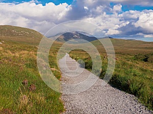 Walk path into mountains, Connemara National park, Ireland, Sunny warm day, Cloudy sky