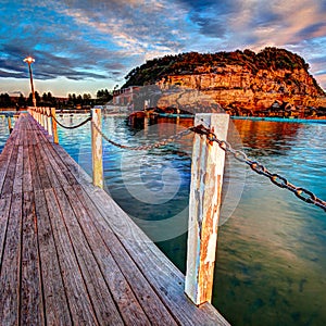 Walk way and guide chain along the side of th ocean swimming pool in early morning 1x1