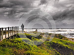 Walker in stormy weather at the edge of the world, Tarkine, Tasmania