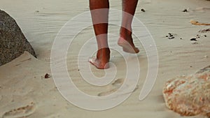 Walkers feet on a white sandy beach with rocks dry