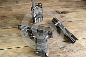 A walkie-talkie, a gun and a flashlight on a wooden table. Devices for the game stalker. Weapons and military equipment.