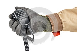 Walkie talkie handheld microphone with spiral connection cord in male hand in black protective glove and brown uniform isolated on