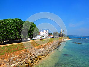 White mosque and lighthouse on the rocky wall along the sealine photo