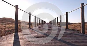 Walking along wooden boardwalk over sand dunes at beach