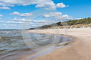 Walking on the Baltic Sea in Palanga, Klaipeda, Lithuania, with waves, cloudy sky, white sandy beach and dunes