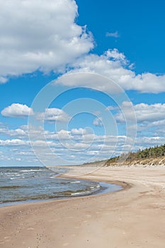 Walking on the Baltic Sea in Palanga, Klaipeda, Lithuania, with waves, cloudy sky, white sandy beach and dunes