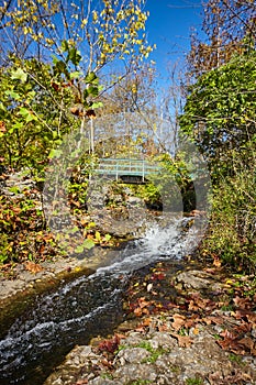 Walking bridge with small waterfall over rocks