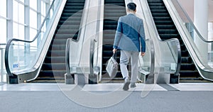 Walking, businessman and escalator in office lobby or entrance to building of work, business or corporate travel. Moving