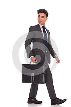 Walking businessman looking back over his shoulder while holding
