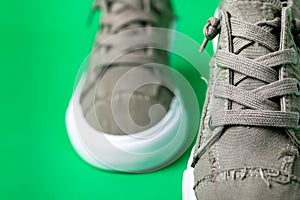 Walking canvas shoes - sneakers. Modern fashion shoes on a green background close-up. Space for text