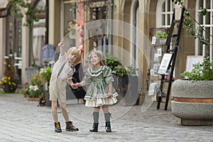 Walking children on the street.A boy shows a girl something in the sky . Photos in retro style . Pavers in the city center.Summer.