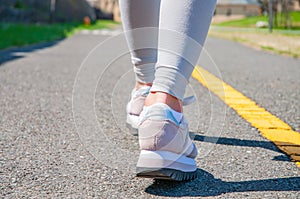 Walking. Close-up of women`s running shoes on a paved trail.