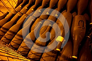 Walking in deep and long undergrounds caves with dusty bottles on racks, making champagne sparkling wine from chardonnay and pinor