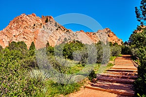 Walking desert path steps with desert plants and red mountains with blue sky background