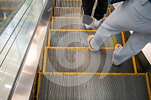 Walking feet wearing flipflop shoe on escalator. Transportation and circulation concept