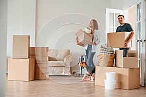 Walking forward with boxes. Young couple with dog are moving to new home