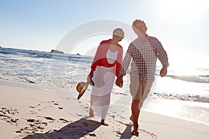 Walking through life hand in hand. a mature couple enjoying a late afternoon walk on the beach.